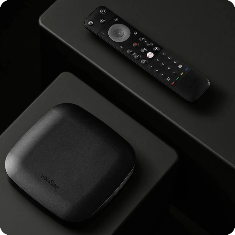 YouSee tv-boks og fjernbetjening placeret på mørk overflade i stilrent produktfoto.